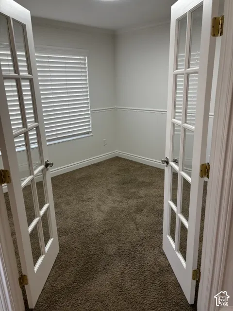 Room with neutral-toned carpeting, crown molding, and wainscoting