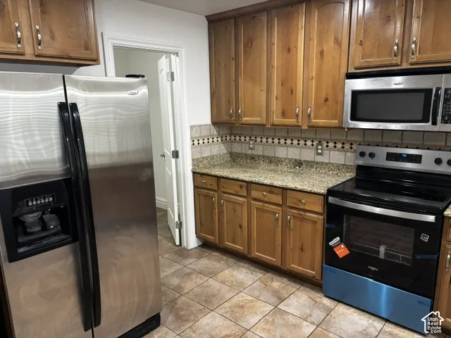 Wood-finish cabinetry paired with granite-style countertops and a decorative tile backsplash