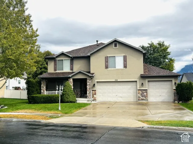 Stucco exterior with stone accents, covered front porch, and an attached two-car garage