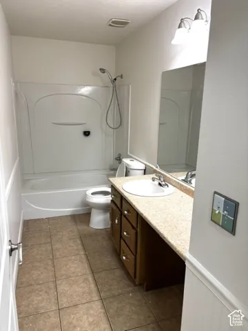 Full bathroom featuring a white tub and shower combination, a single vanity with a white basin, a light-colored countertop, and a tiled floor