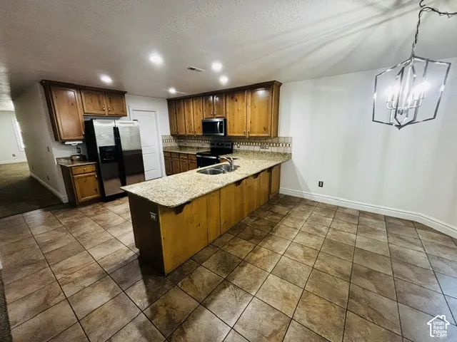 Kitchen featuring wood cabinetry, granite-style countertops, stainless steel appliances, and tile flooring