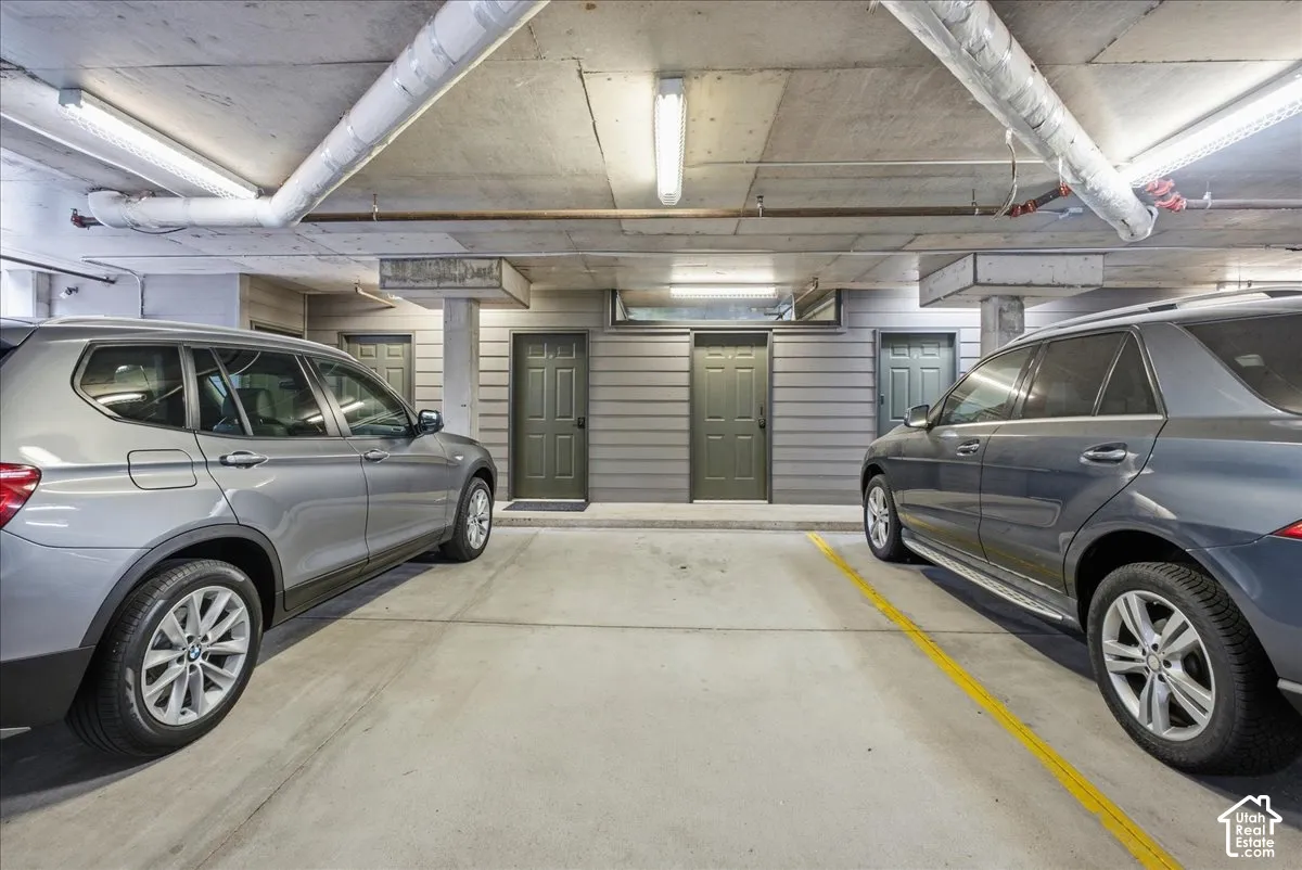 Underground parking garage featuring concrete flooring and exposed ceiling pipes