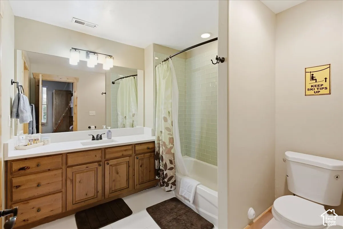 Extended vanity with wood-finish cabinetry, integrated sink, and a large mirror
