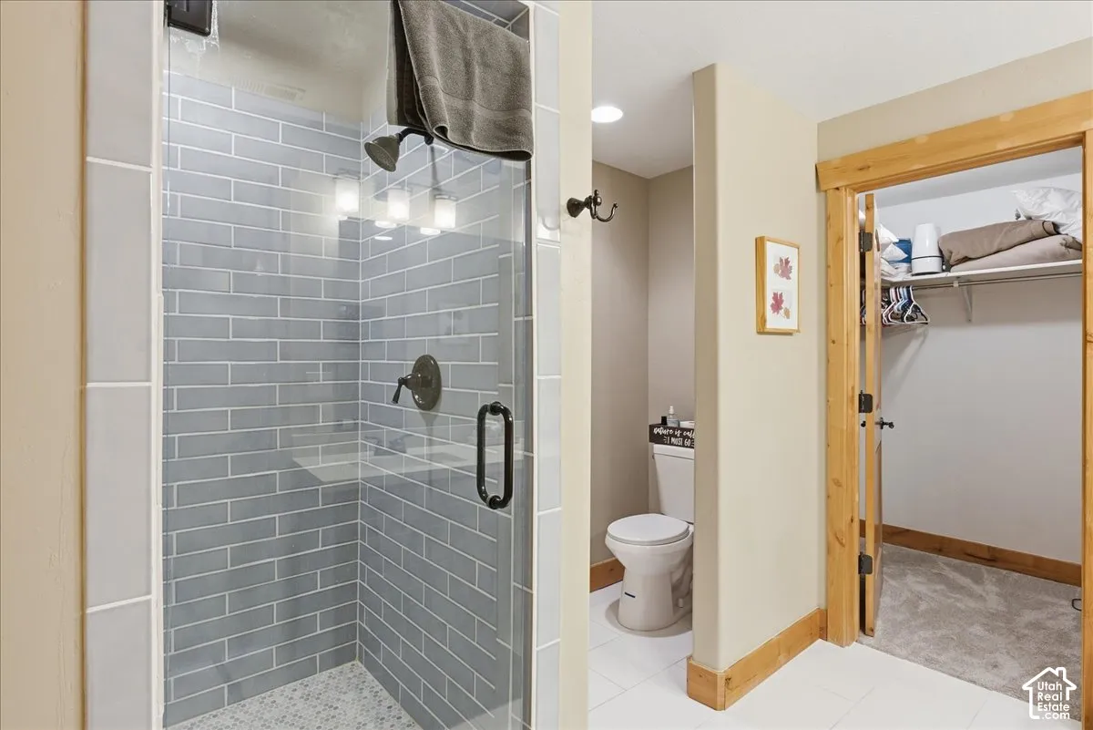 Glass-enclosed shower with subway tile surround, matte black fixtures, and mosaic tile flooring