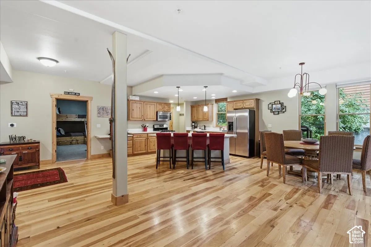 Open-concept living space featuring wood-finish flooring, a kitchen with wood cabinetry, and a dining area with a chandelier
