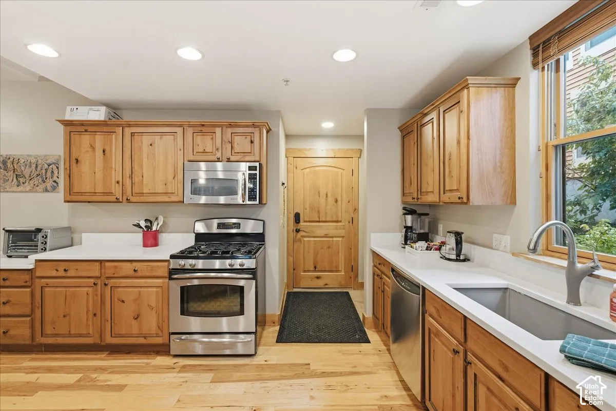 Full kitchen featuring wood-finish cabinetry, stainless steel appliances, white countertops, and wood-finish flooring