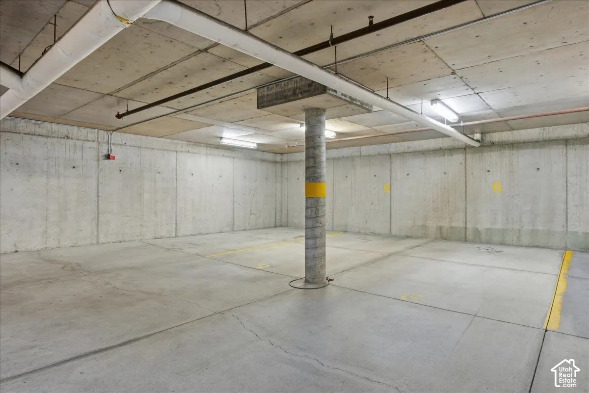 Concrete flooring, concrete walls, concrete ceiling, exposed piping, fluorescent lighting