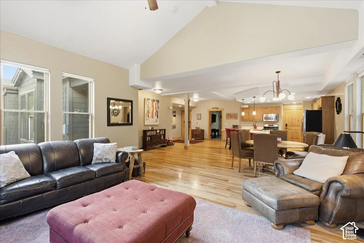 Vaulted ceiling living area featuring wood-finish flooring, recessed lighting, and large windows