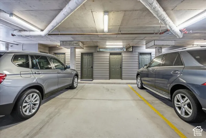 Underground parking garage featuring concrete flooring and exposed ceiling pipes