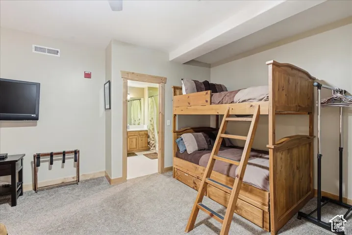 Carpeted room featuring a wood-finish bunk bed with a ladder, a built-in television mount, and a wood-trimmed doorway