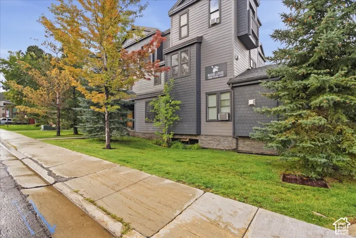 Multi-story exterior with horizontal siding and shingle accents, featuring multiple window units and a stone foundation