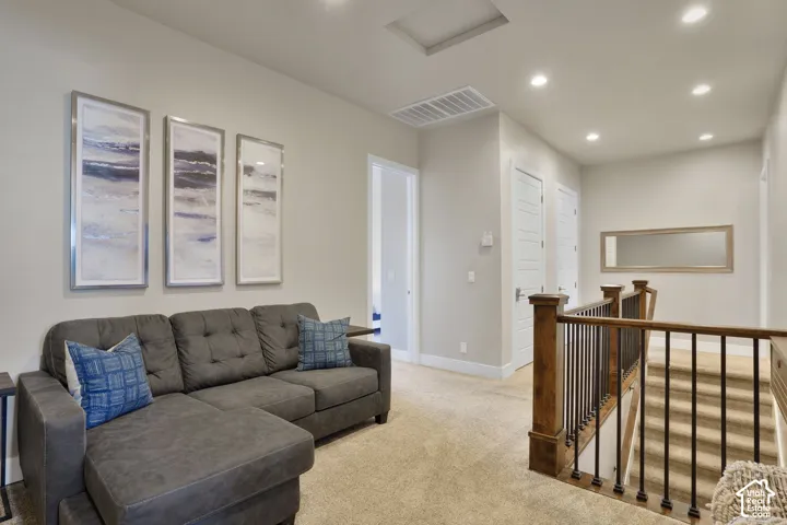 Carpeted landing featuring recessed lighting, a wood newel post with black metal balusters, and white paneled doors
