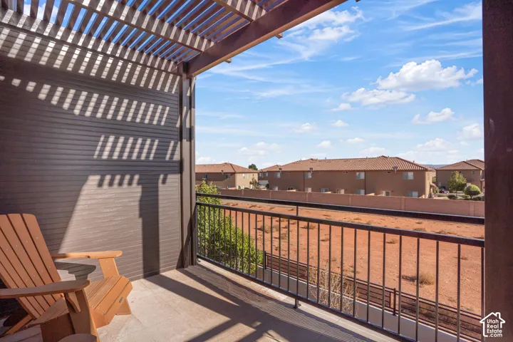 Balcony featuring a slatted pergola, durable exterior siding, and a black metal railing