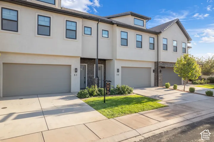 Stucco exterior with dark-framed windows, attached garages, stone facade accents, and concrete driveways