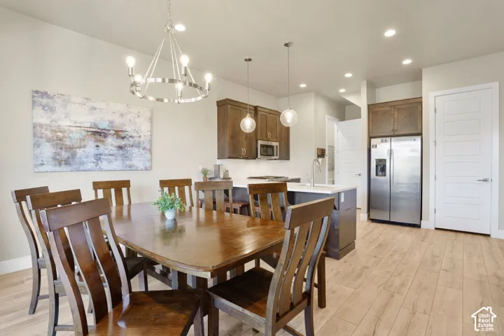 Open-concept living space with light wood-finish flooring, recessed lighting, and a contemporary chandelier