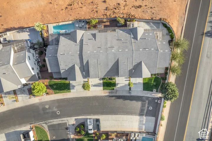 Multi-unit residential structure with a shingle roof, well-maintained landscaping, and an integrated swimming pool