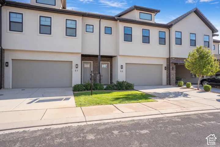 Stucco exterior with stone accents, integrated garages, front entry doors with transom windows, and dark-framed windows