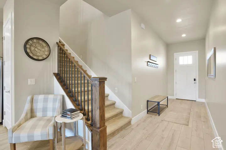 Hard-surface flooring, staircase with wood handrail and iron balusters, recessed lighting, white front entry door with glass panels