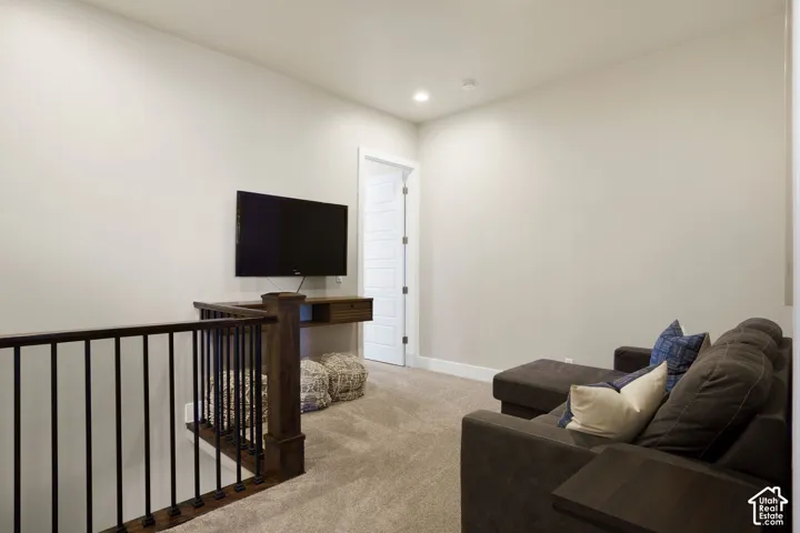 Carpeted flooring, recessed lighting, and a wood-finish railing with black metal balusters