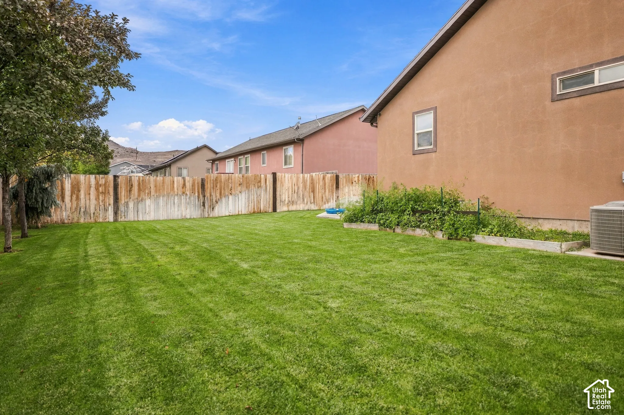 Expansive backyard featuring a manicured lawn, wood privacy fencing, and mature trees
