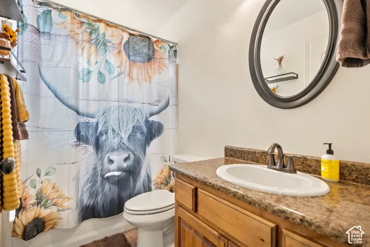 Built-in wood-finish vanity with a drop-in sink, dark countertop, and bronze-finish faucet