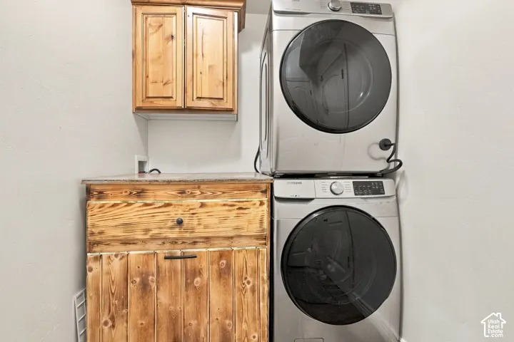 Stacked stainless steel appliances, wood cabinetry, wood-finish countertop, and built-in storage