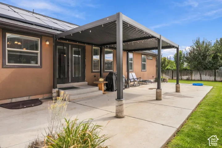 Expansive concrete patio with a modern louvered pergola featuring integrated lighting