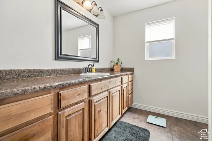 Wood-finish vanity with ample storage, integrated sink, and dark-toned countertop