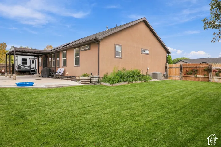 Expansive backyard featuring a manicured lawn, concrete patio, and a covered pergola