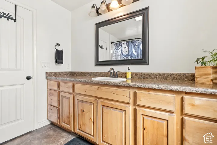 Vanity with a granite-style countertop, integrated sink, and light wood-finish cabinetry