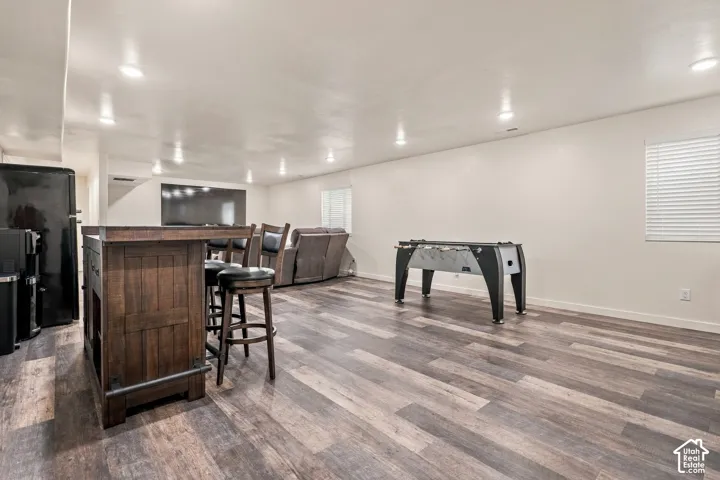 Spacious recreation area featuring wood-finish flooring, recessed lighting, and a built-in bar