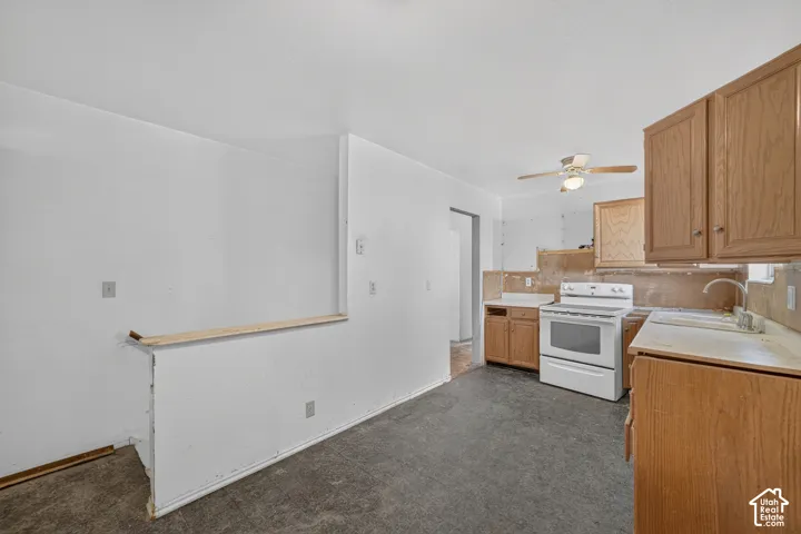 Kitchen space featuring wood-finish cabinetry, white freestanding range, and a ceiling fan