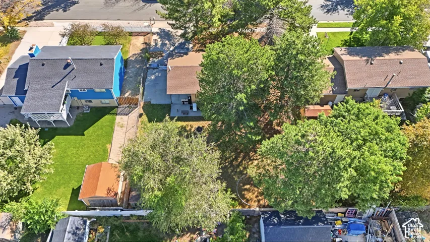 Property exterior featuring a fenced yard, mature trees, an outbuilding, and a paved driveway