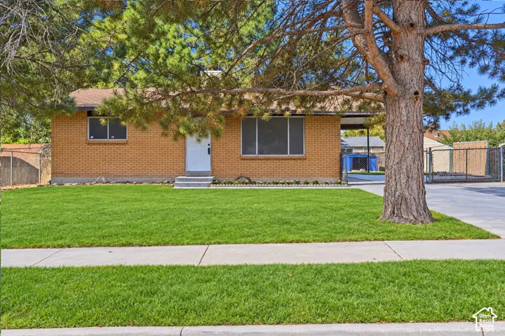 Brick exterior, pitched roof, well-maintained lawn, mature front tree, and paved driveway