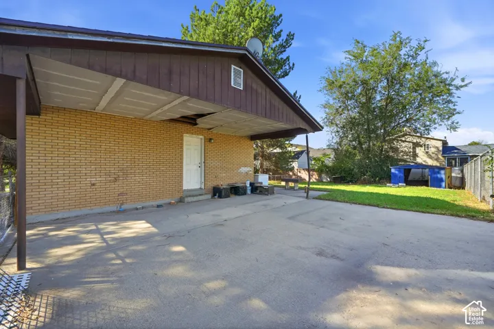 Carport with concrete slab, brick exterior, and a side entry door