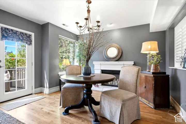 Wood-finish flooring, white fireplace with mantle, white plantation shutters, and a classic chandelier
