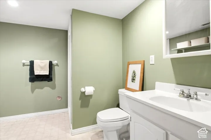White vanity with integrated sink, chrome faucet, wall-mounted medicine cabinet, white toilet, and light-toned flooring