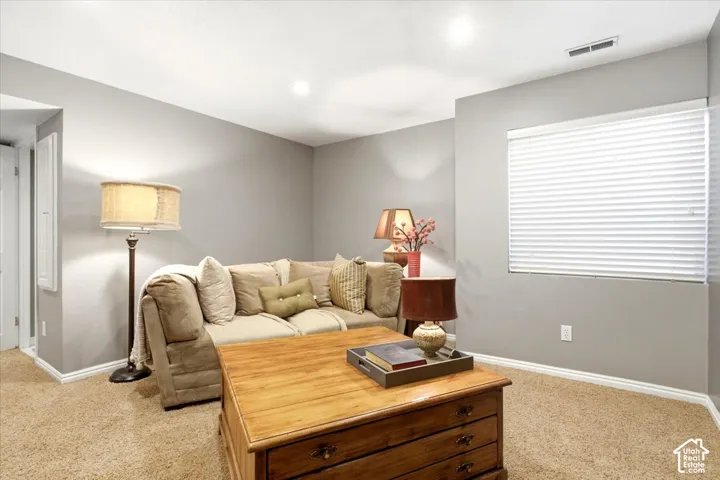 Recessed lighting illuminates the carpeted flooring and light grey walls