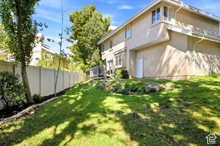 Expansive backyard featuring a manicured lawn, full-height privacy fencing, and mature trees