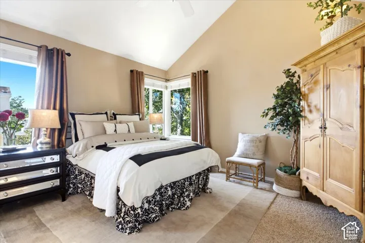 Vaulted ceiling, corner windows, light-toned walls, and neutral-toned carpeting
