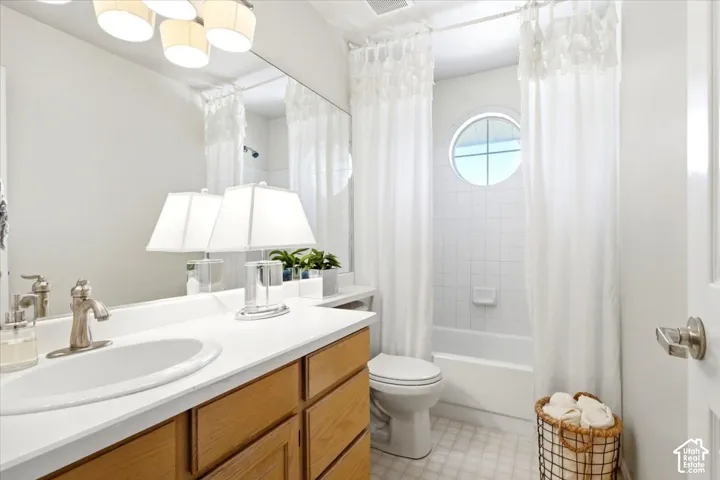 Bathroom featuring a circular window, white tiled shower, white countertop with an integrated sink, and wood-finish cabinetry