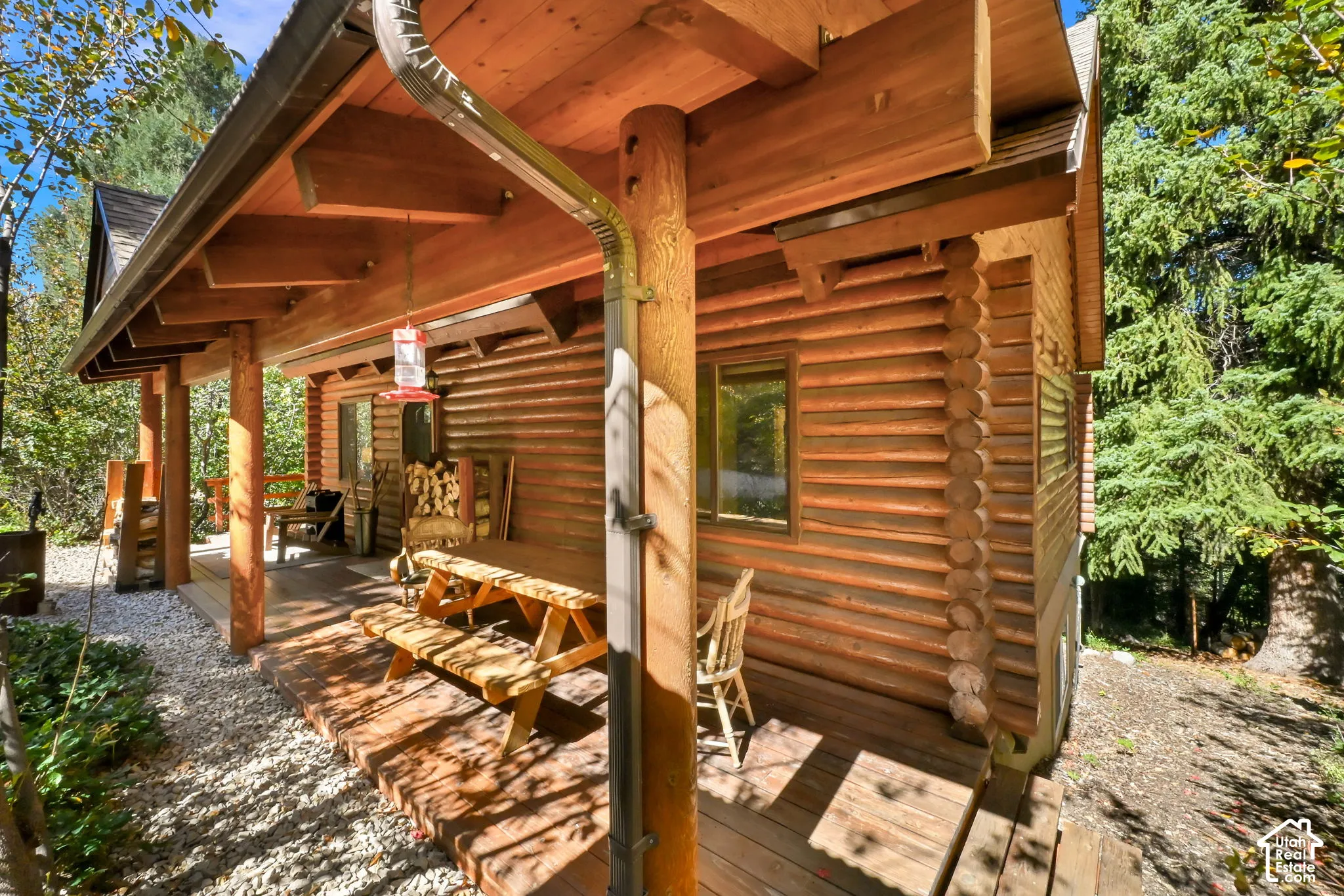 Log cabin exterior featuring a covered porch, wood plank decking, and a gravel perimeter