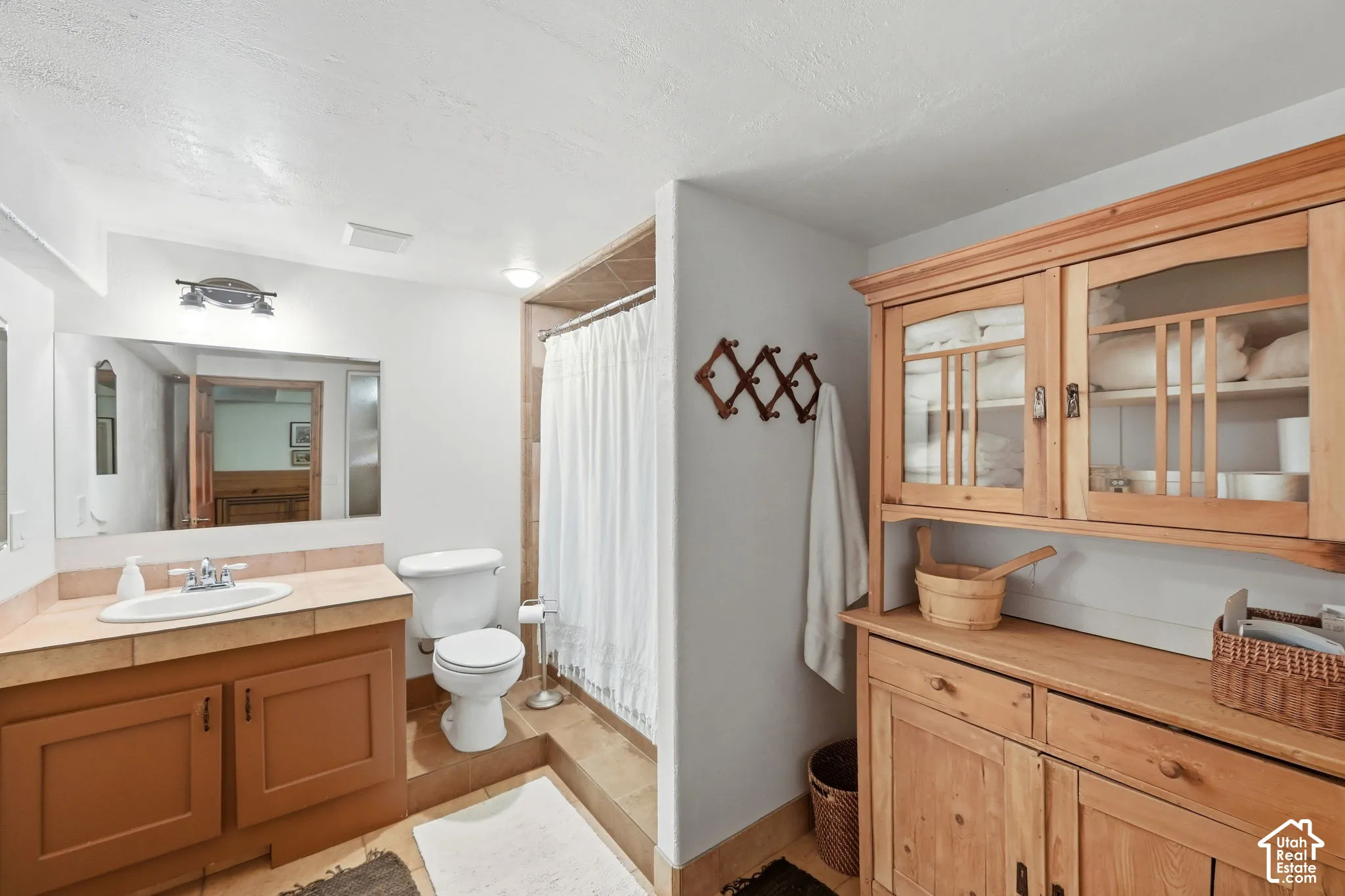 Vanity with a single basin, tiled countertop, and wood-finish cabinetry