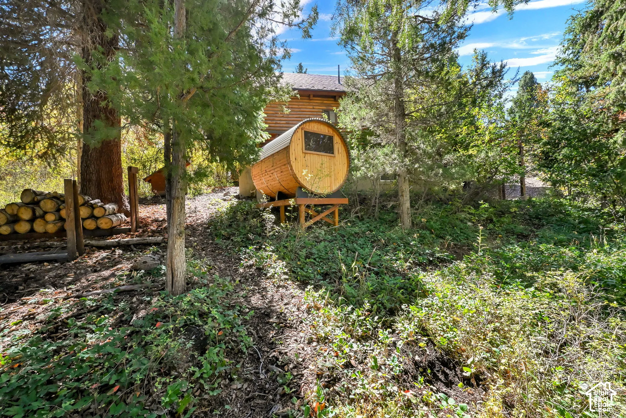 Barrel-style sauna with a small window, set on an elevated wooden platform