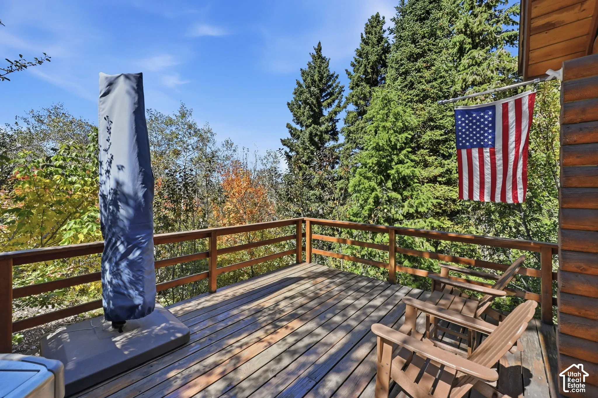 Expansive wood deck with a wood railing, surrounded by mature trees