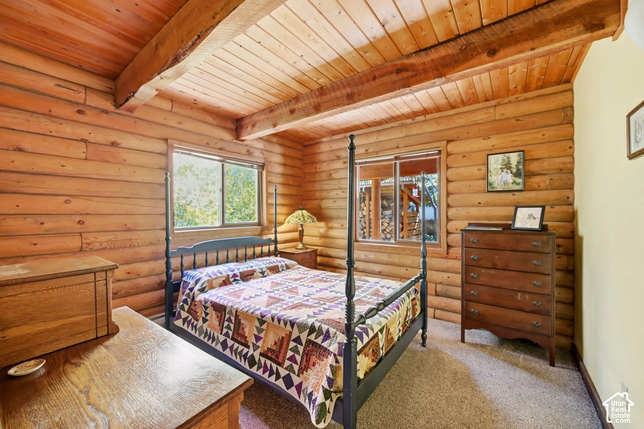Log wall construction with exposed wood ceiling beams, wood-planked ceiling, and wood-framed windows