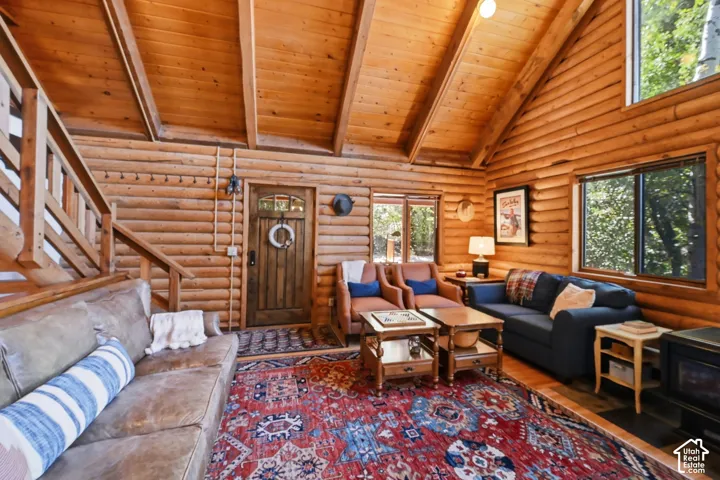 Vaulted wood-paneled ceiling, exposed wood beams, log wall construction, wood framed windows, and a wood entry door with leaded glass