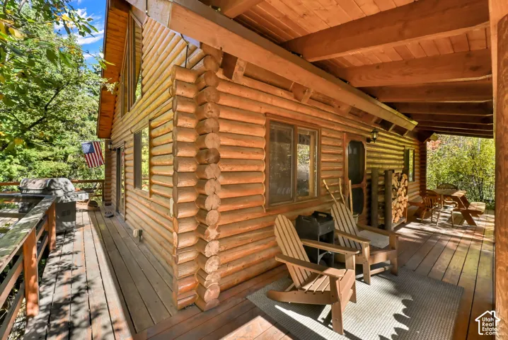 Log cabin exterior with an expansive wood deck, exposed wood beams, and a covered porch