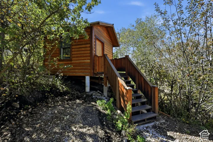 Log cabin-style exterior with wood siding, elevated foundation, and wood staircase with handrails