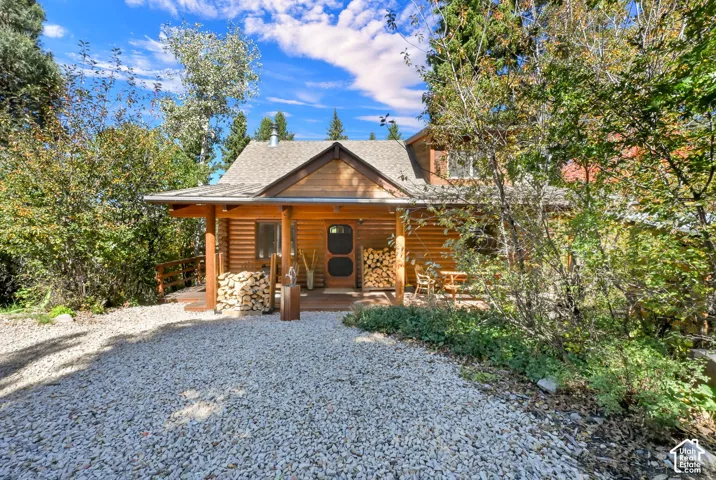 Log-sided exterior with a covered front porch and a gravel driveway